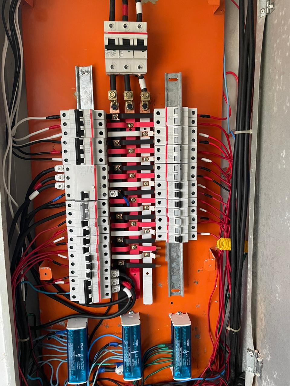 Painel elétrico industrial com fundo laranja e componentes elétricos